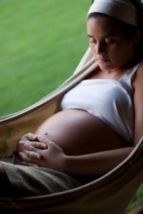 Pregnant woman resting in hammock.